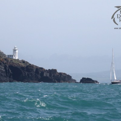 yacht sailing past lighthouse