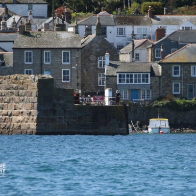 Old stone houses by a harbor with a small boat on the water.