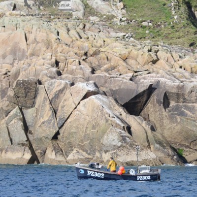A small fishing boat labeled PZ302 near rocky cliffs and grassy area.