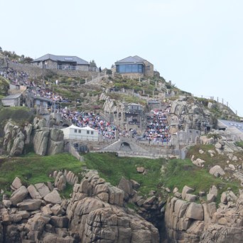 Cliffside open-air theater with tiered seating overlooking the sea.