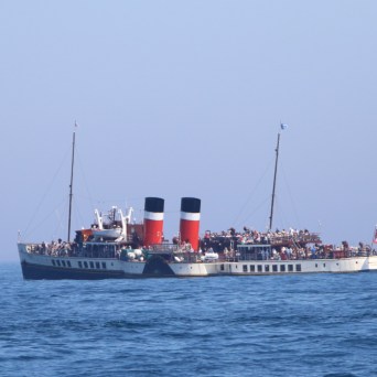 Large vintage steamship with two red and black funnels on calm sea.