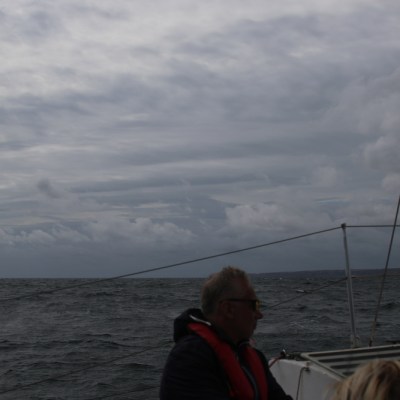 People sailing on a boat under a cloudy sky.