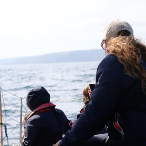 People on a boat with the ocean and distant hills in the background.