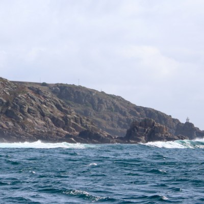 Rocky coastline with waves and cloudy sky.