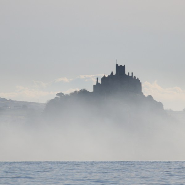 Misty silhouette of a castle on a hill by the sea.